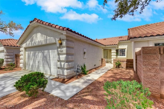 view of side of property featuring a tile roof, an attached garage, and stucco siding