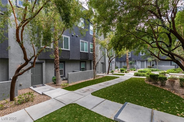 multi unit property with a residential view, stucco siding, and a front lawn