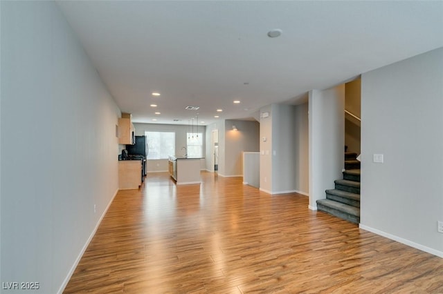 unfurnished living room featuring light wood finished floors, stairway, recessed lighting, and baseboards