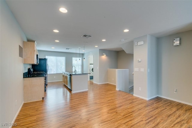 kitchen with recessed lighting, a sink, light wood-style floors, open floor plan, and baseboards