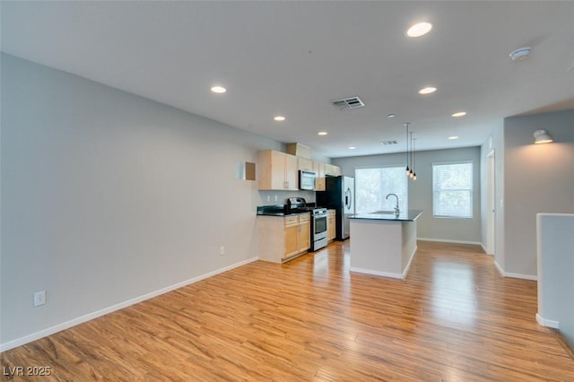 kitchen with stainless steel appliances, a sink, light wood finished floors, recessed lighting, and baseboards