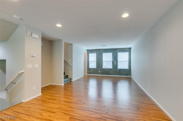 empty room with wood finished floors, baseboards, recessed lighting, a smoke detector, and stairway