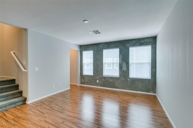 empty room with wood finished floors, stairs, and baseboards
