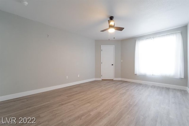 empty room with light wood finished floors, baseboards, and ceiling fan