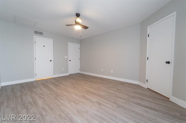 unfurnished bedroom featuring light wood finished floors, attic access, baseboards, and visible vents