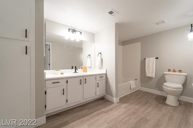 bathroom with wood finished floors, vanity, baseboards, toilet, and visible vents