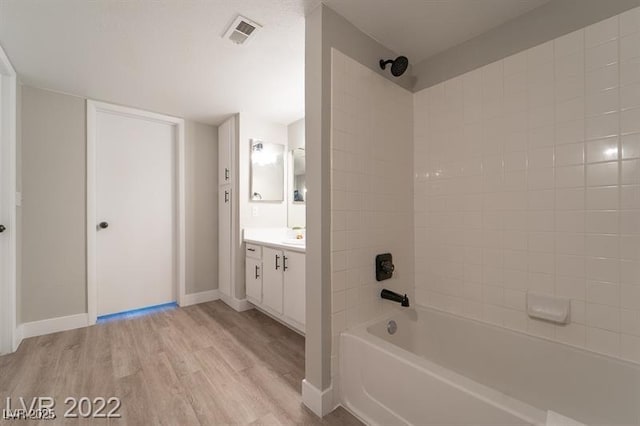 bathroom with wood finished floors, vanity, shower / bath combination, baseboards, and visible vents