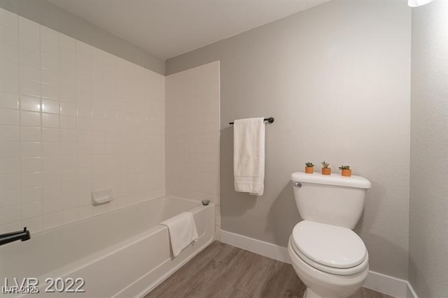 full bathroom with baseboards, wood finished floors, tub / shower combination, and toilet