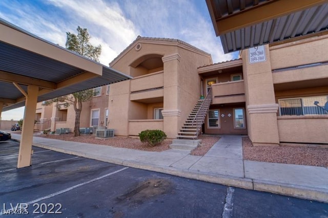 view of building exterior with stairway and covered and uncovered parking