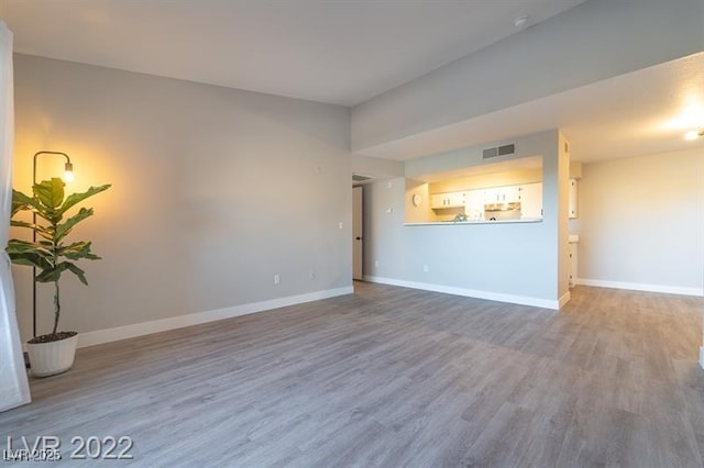 unfurnished living room with baseboards, wood finished floors, and visible vents