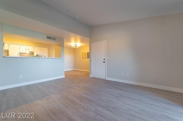 unfurnished room featuring baseboards, wood finished floors, and visible vents