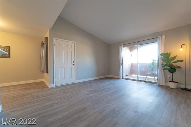 spare room with wood finished floors, lofted ceiling, and baseboards