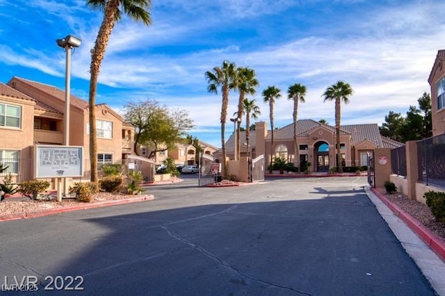 view of road with a gated entry, curbs, street lighting, and a residential view
