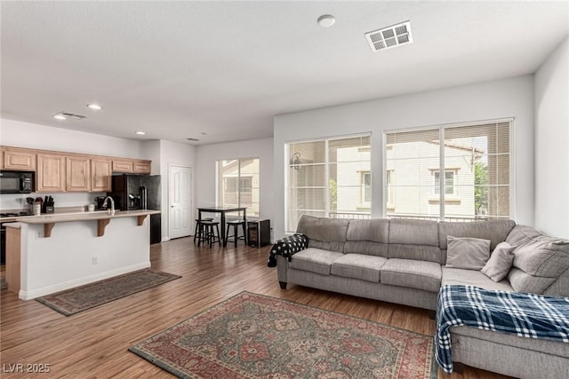 living room with wood finished floors, visible vents, and recessed lighting