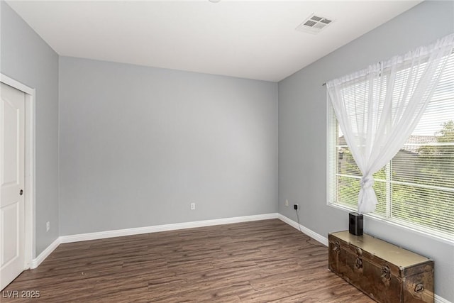 unfurnished room with visible vents, wood finished floors, and a wealth of natural light