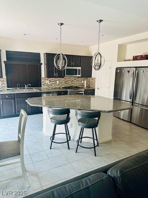 kitchen featuring light tile patterned floors, a center island, a sink, stainless steel appliances, and tasteful backsplash