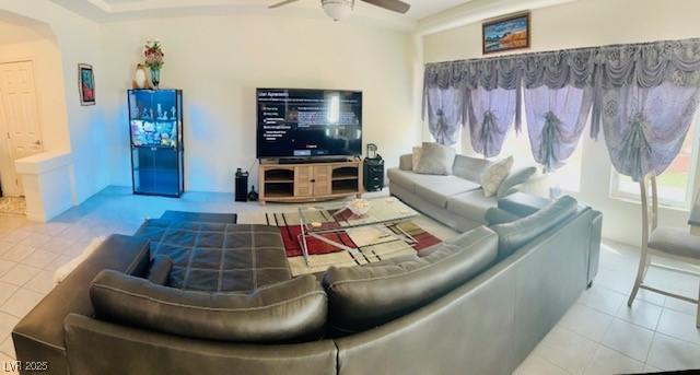 tiled living room with ceiling fan and arched walkways