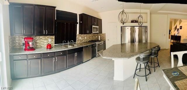 kitchen featuring a sink, a kitchen breakfast bar, appliances with stainless steel finishes, a kitchen island, and tasteful backsplash