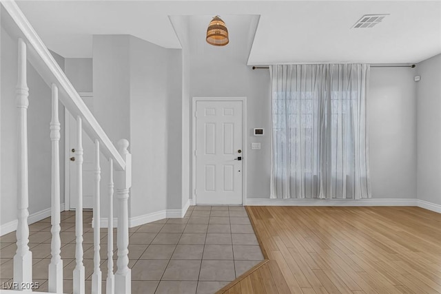 foyer entrance featuring stairway, baseboards, wood finished floors, and visible vents