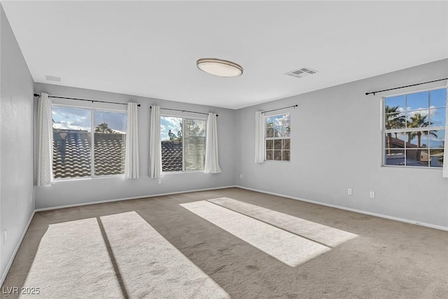 carpeted empty room featuring baseboards, a healthy amount of sunlight, and visible vents