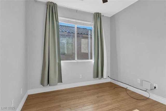 unfurnished room with baseboards and wood finished floors
