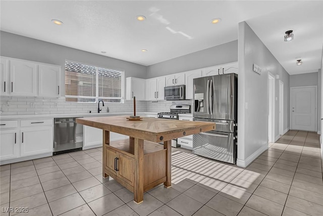 kitchen with light tile patterned floors, decorative backsplash, butcher block countertops, and appliances with stainless steel finishes