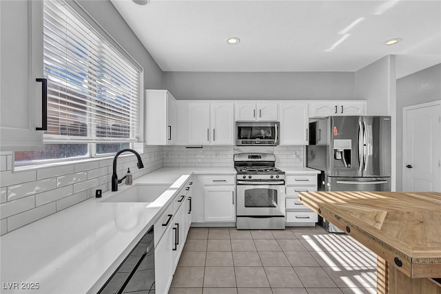 kitchen featuring decorative backsplash, stainless steel appliances, a sink, and light tile patterned floors