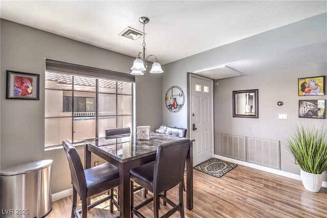 dining space featuring baseboards, visible vents, a notable chandelier, and light wood finished floors