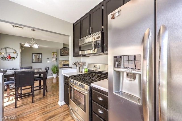 4809 S Torrey Pines Dr Unit 201, Las Vegas, NV 89103 - kitchen with appliances with stainless steel finishes, light wood-style floors, decorative light fixtures, a chandelier, and light countertops