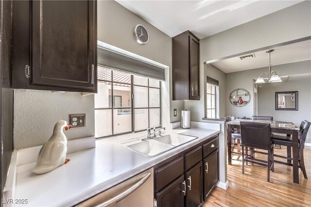 kitchen featuring a sink, light wood-type flooring, dark brown cabinetry, visible vents, and light countertops