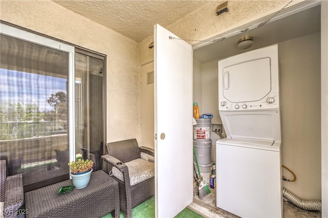 laundry area featuring stacked washer / dryer, a textured ceiling, and laundry area