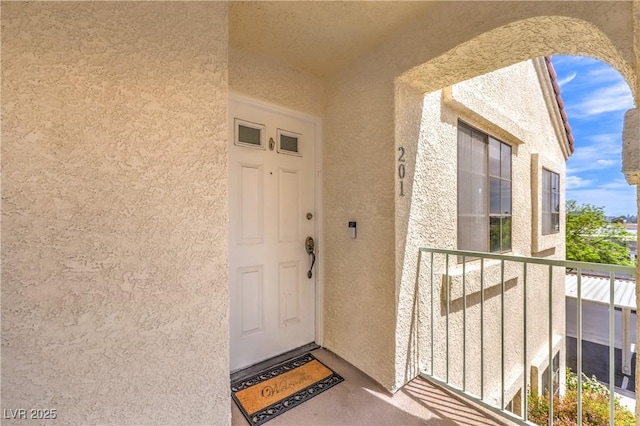 doorway to property featuring a balcony and stucco siding