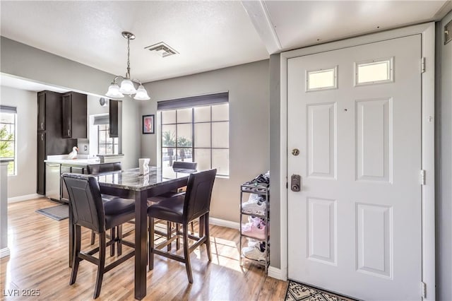 dining room with visible vents, light wood-style flooring, a chandelier, and baseboards