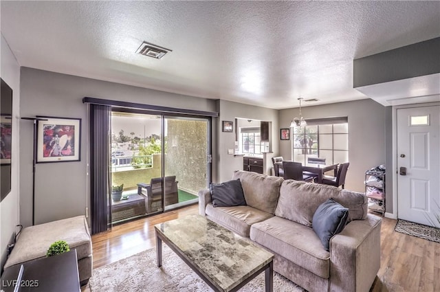living area with visible vents, light wood-type flooring, and a textured ceiling