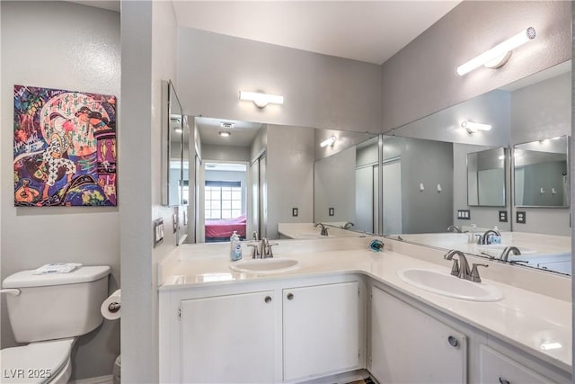 bathroom featuring toilet, double vanity, a sink, and connected bathroom
