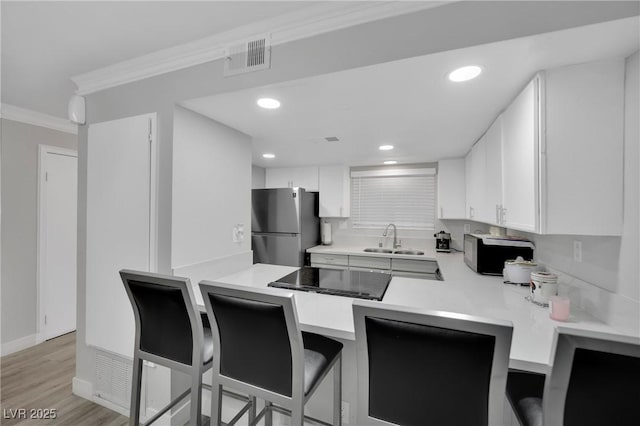 2080 Karen Ave Unit 1, Las Vegas, NV 89169 - kitchen featuring freestanding refrigerator, a sink, crown molding, light countertops, and white cabinetry