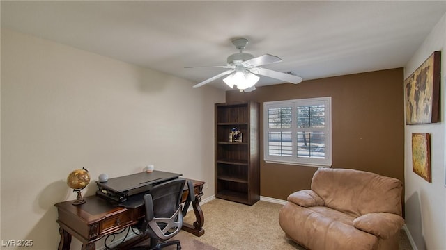 office space featuring a ceiling fan, light colored carpet, and baseboards