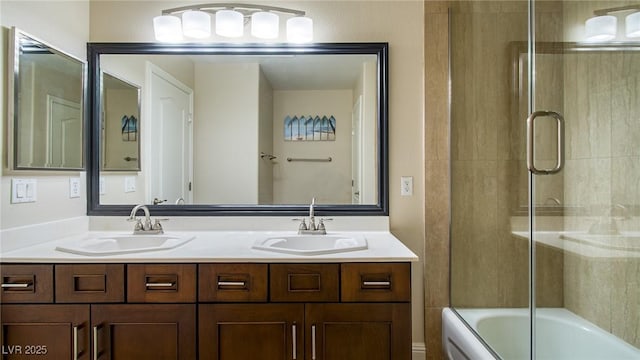 bathroom with combined bath / shower with glass door, double vanity, and a sink