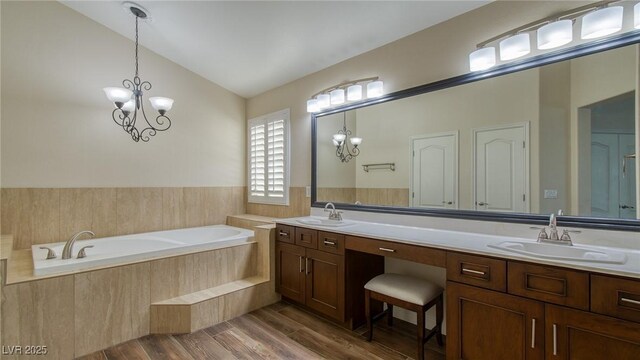 full bathroom with a bath, wood finished floors, double vanity, and a sink