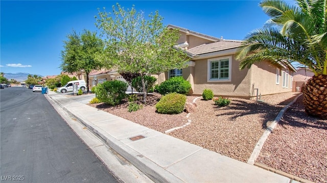 view of property hidden behind natural elements featuring stucco siding and a tiled roof