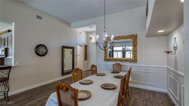 dining space featuring visible vents, wood finished floors, a notable chandelier, and arched walkways