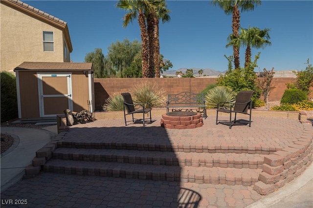 view of patio with a fenced backyard, an outbuilding, an outdoor fire pit, and a storage unit