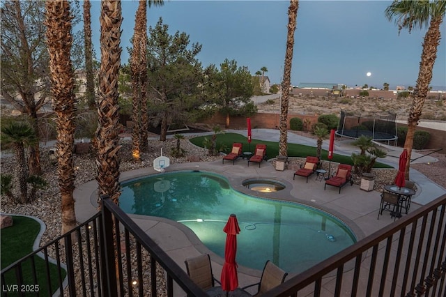 outdoor pool featuring a trampoline, a patio, and an in ground hot tub