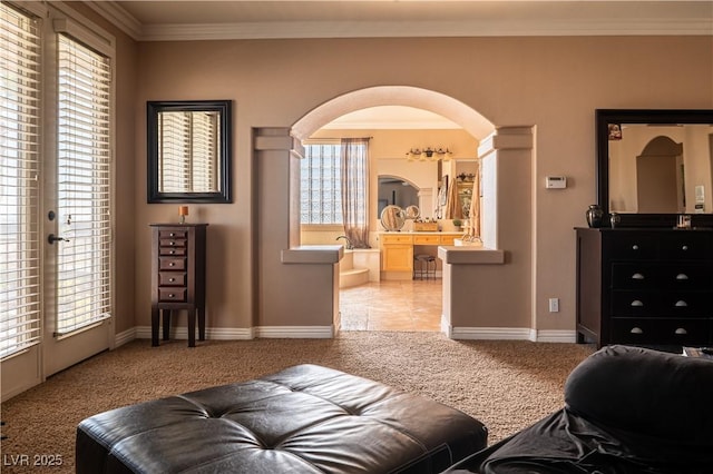 living area with baseboards, arched walkways, light colored carpet, and crown molding