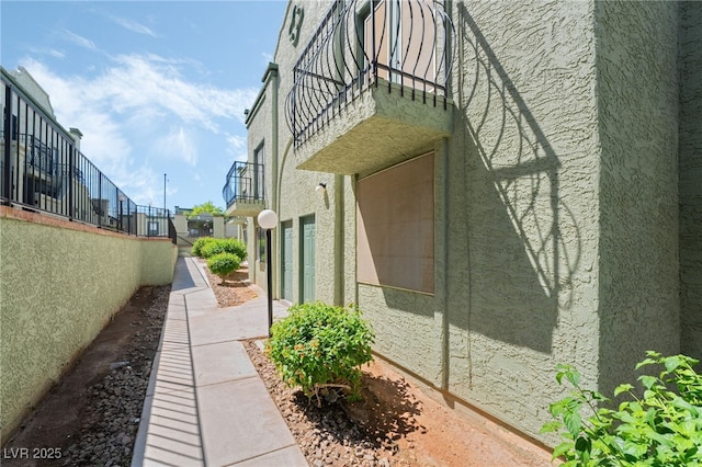 view of side of property featuring a balcony and stucco siding