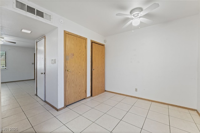 unfurnished bedroom with light tile patterned flooring, visible vents, a ceiling fan, and baseboards
