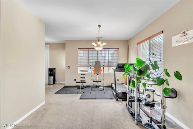 exercise room with baseboards, a chandelier, and carpet flooring