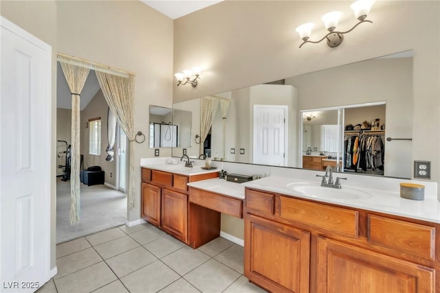 bathroom with tile patterned flooring, double vanity, a chandelier, a walk in closet, and baseboards