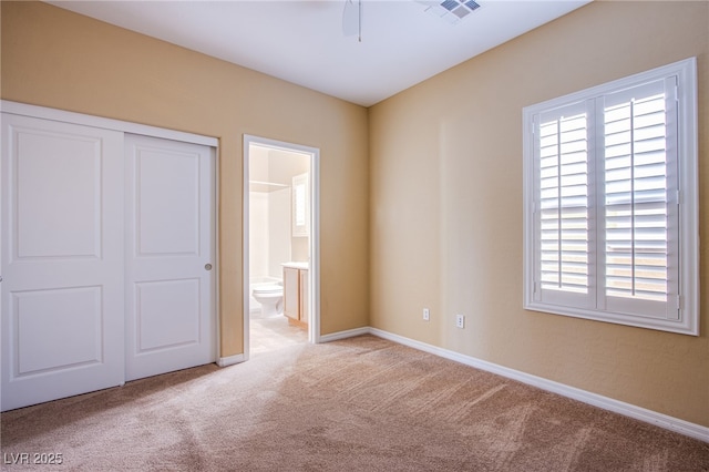 unfurnished bedroom with carpet flooring, ensuite bathroom, baseboards, visible vents, and a closet