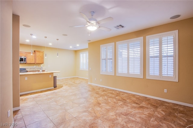 unfurnished living room featuring baseboards, a ceiling fan, a sink, and visible vents